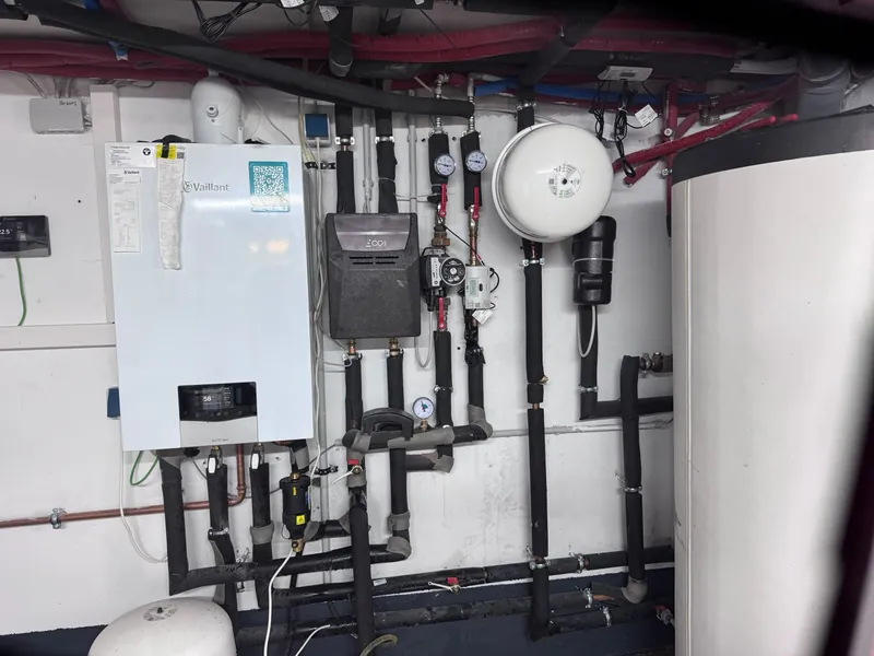 Installierte Heizungsanlage: Wandgerät, Verteiler mit Manometern, Ausdehnungsgefäß und Speicher mit gedämmten Leitungen
