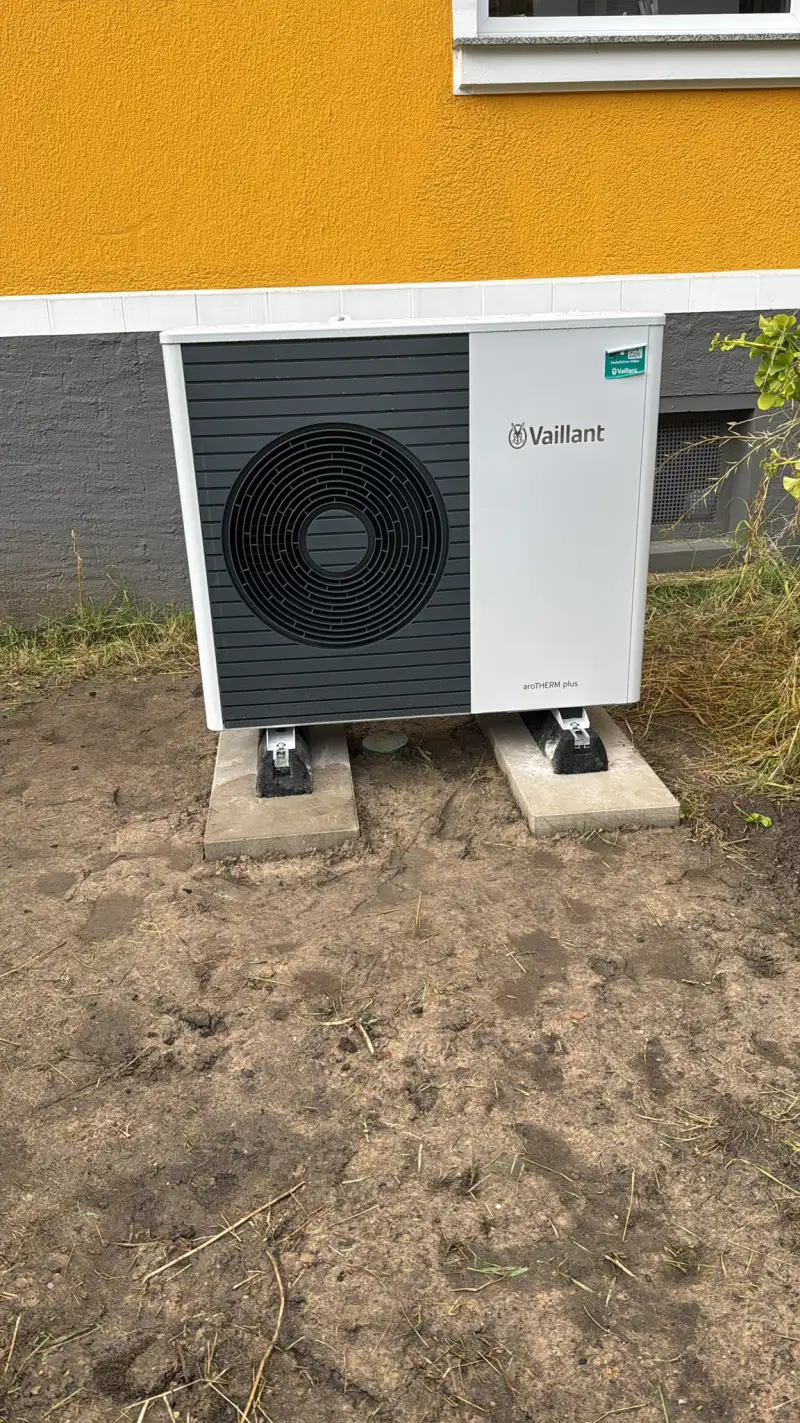 Außeneinheit einer Vaillant Luft-Wasser-Wärmepumpe auf Betonsockeln vor einer Hauswand